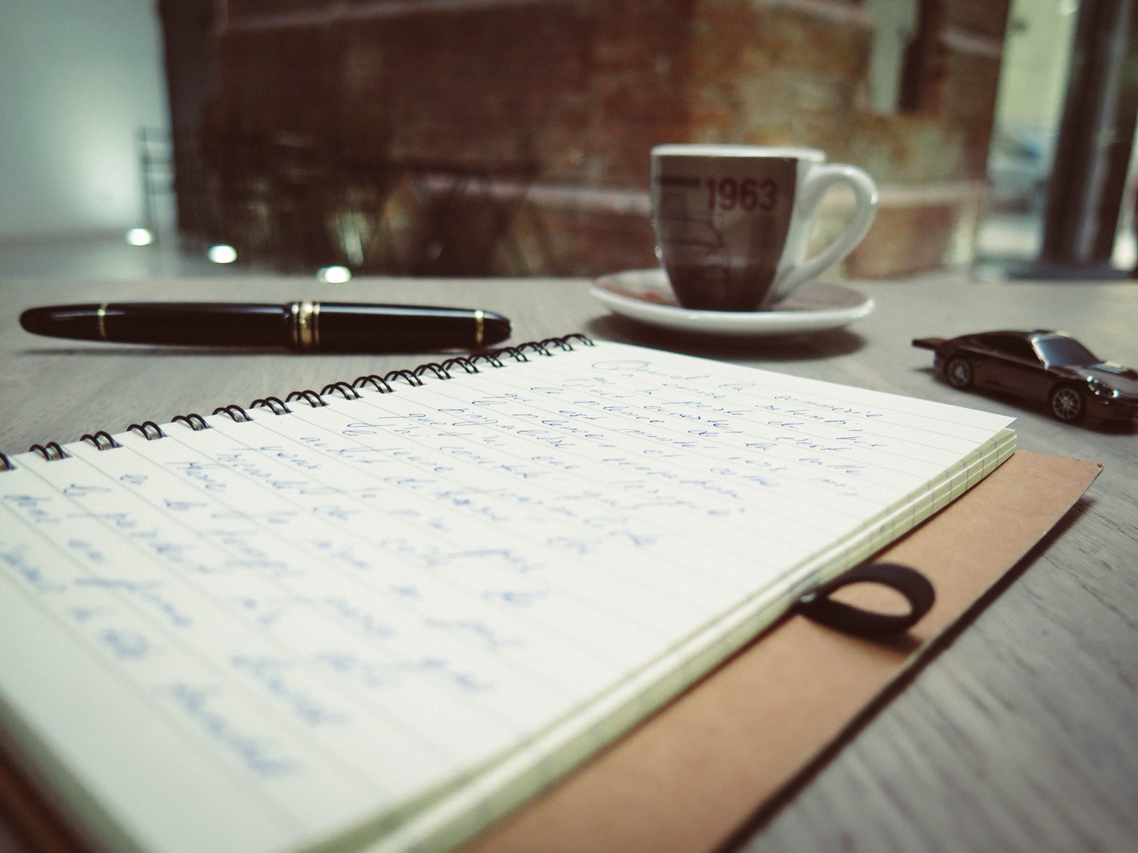 Handwritten notebook beside a fountain pen and an espresso cup