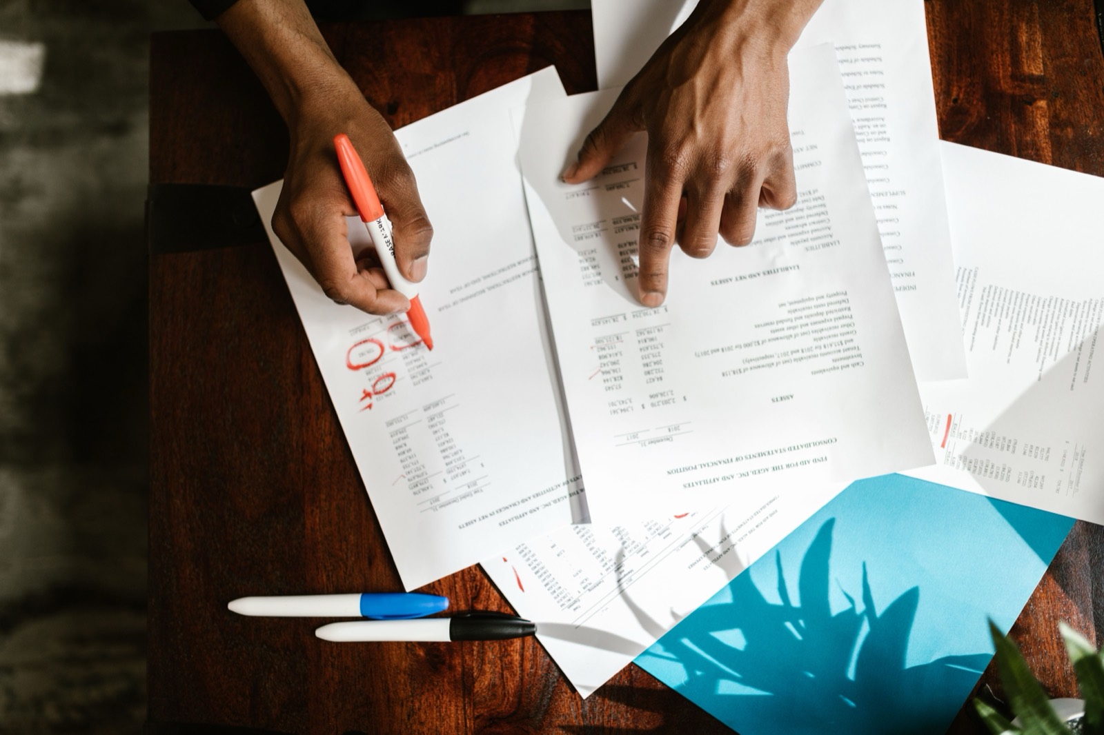 Hands marking up printed documents with a red pen