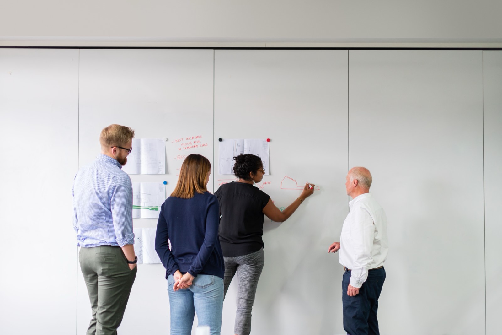 Engineering team working through diagrams at a whiteboard