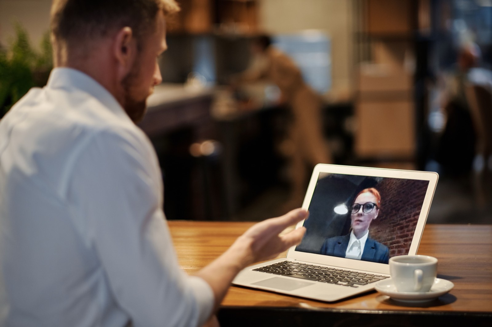 Person waving to a colleague on a laptop video call